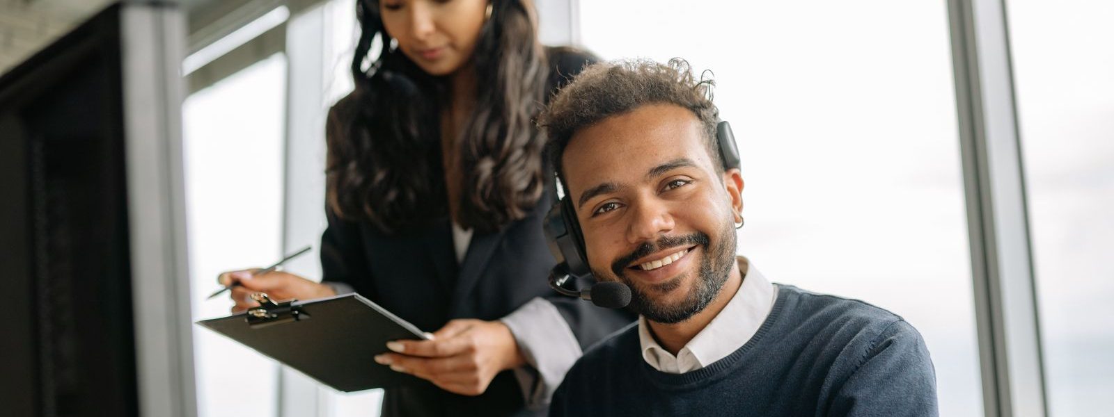 A Transint support agent wearing a headset, smiling at their computer